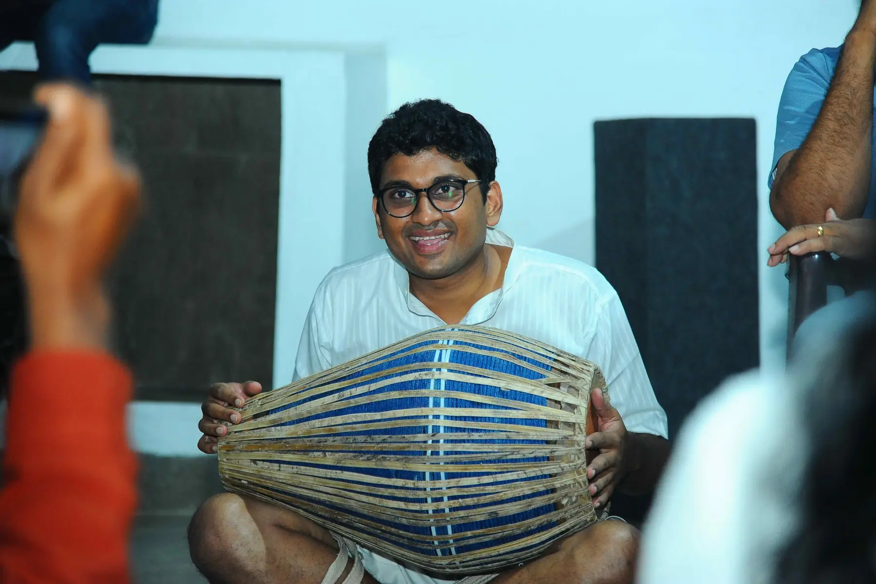 A participant smiling as he plays the mridangam