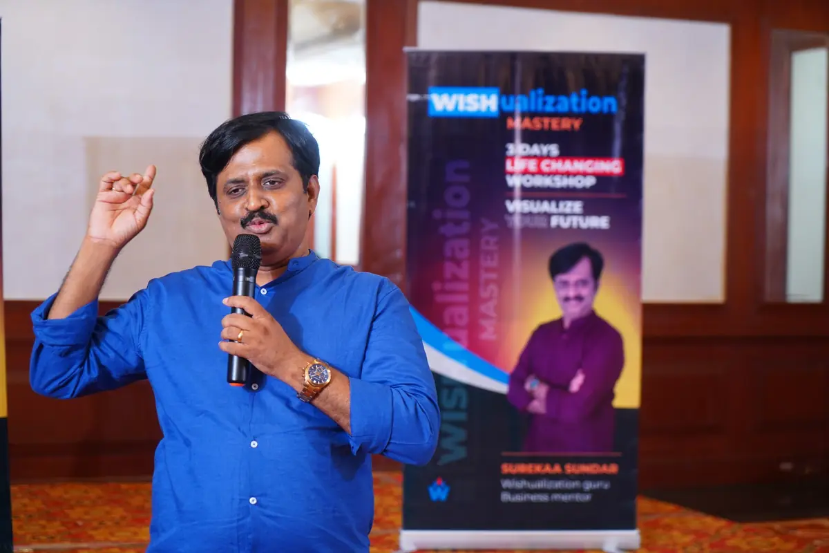 Surekaa Sundar teaching with a microphone beside the WISHualization banner